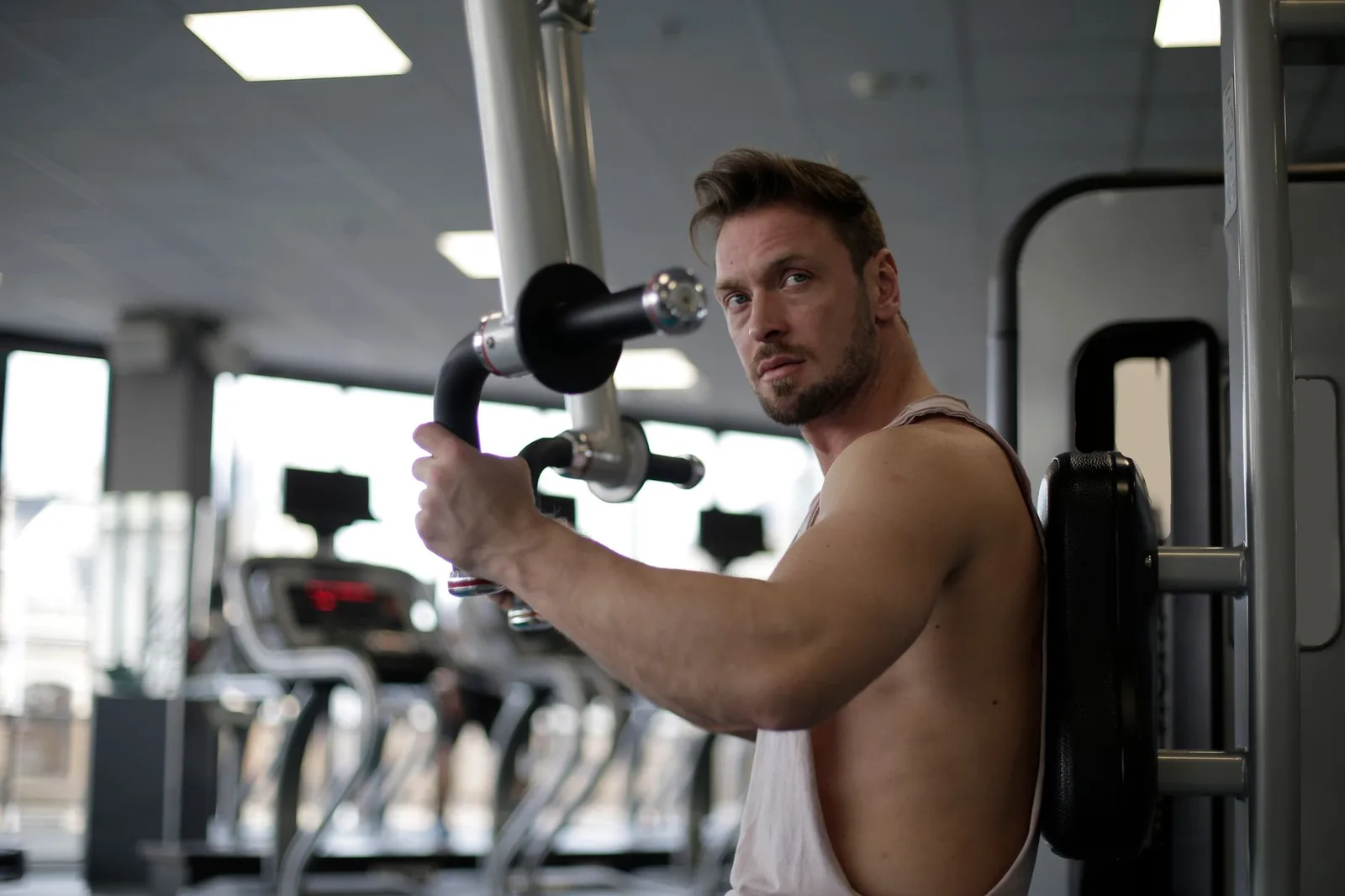 Focused man working out in a gym, showcasing biceps and determination.