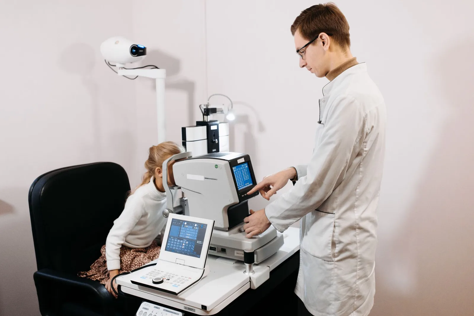 A professional optometrist examines a child's eyes using advanced equipment.