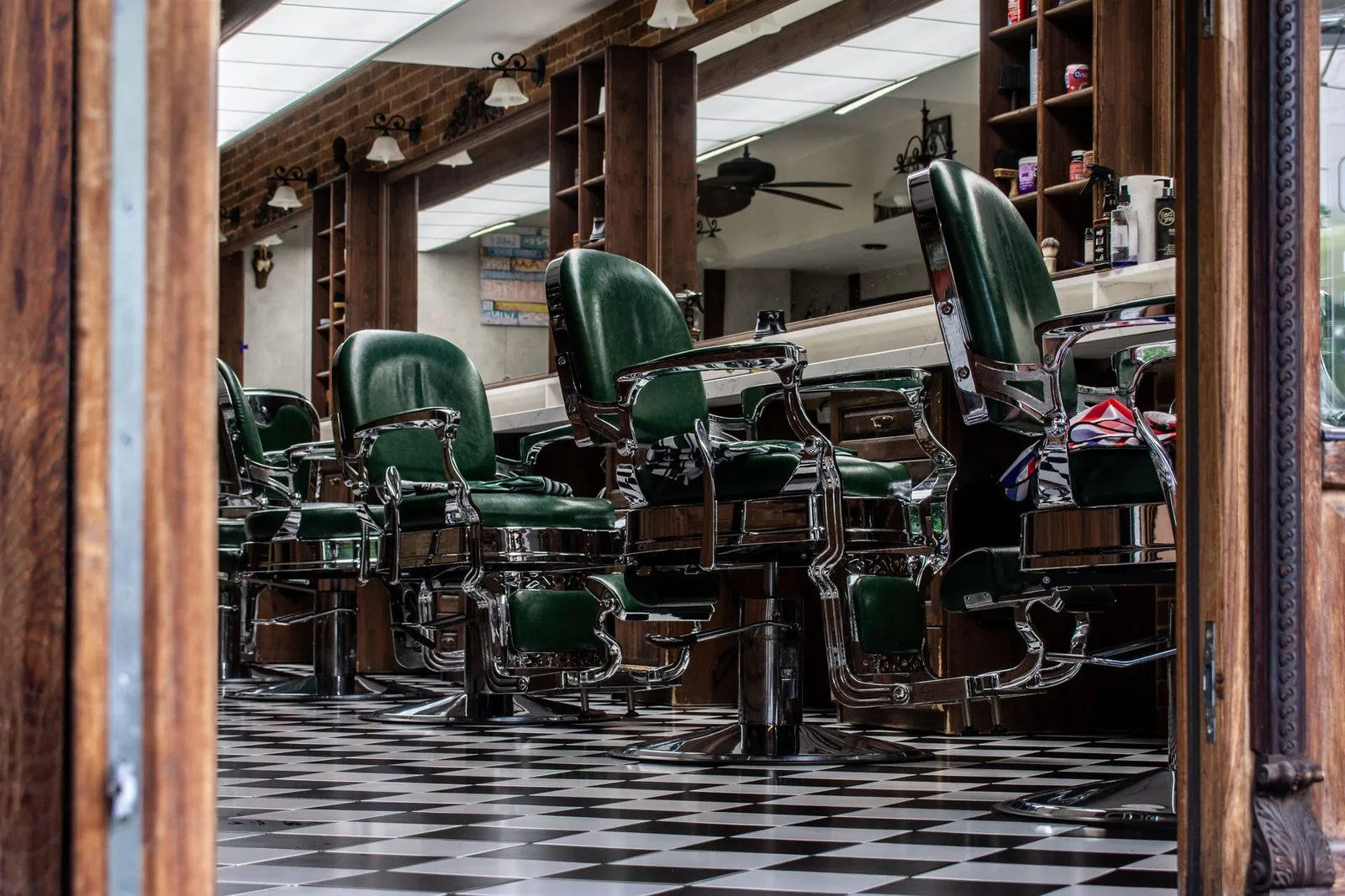 Charming vintage barber shop with classic green chairs and checkered floor tiles.
