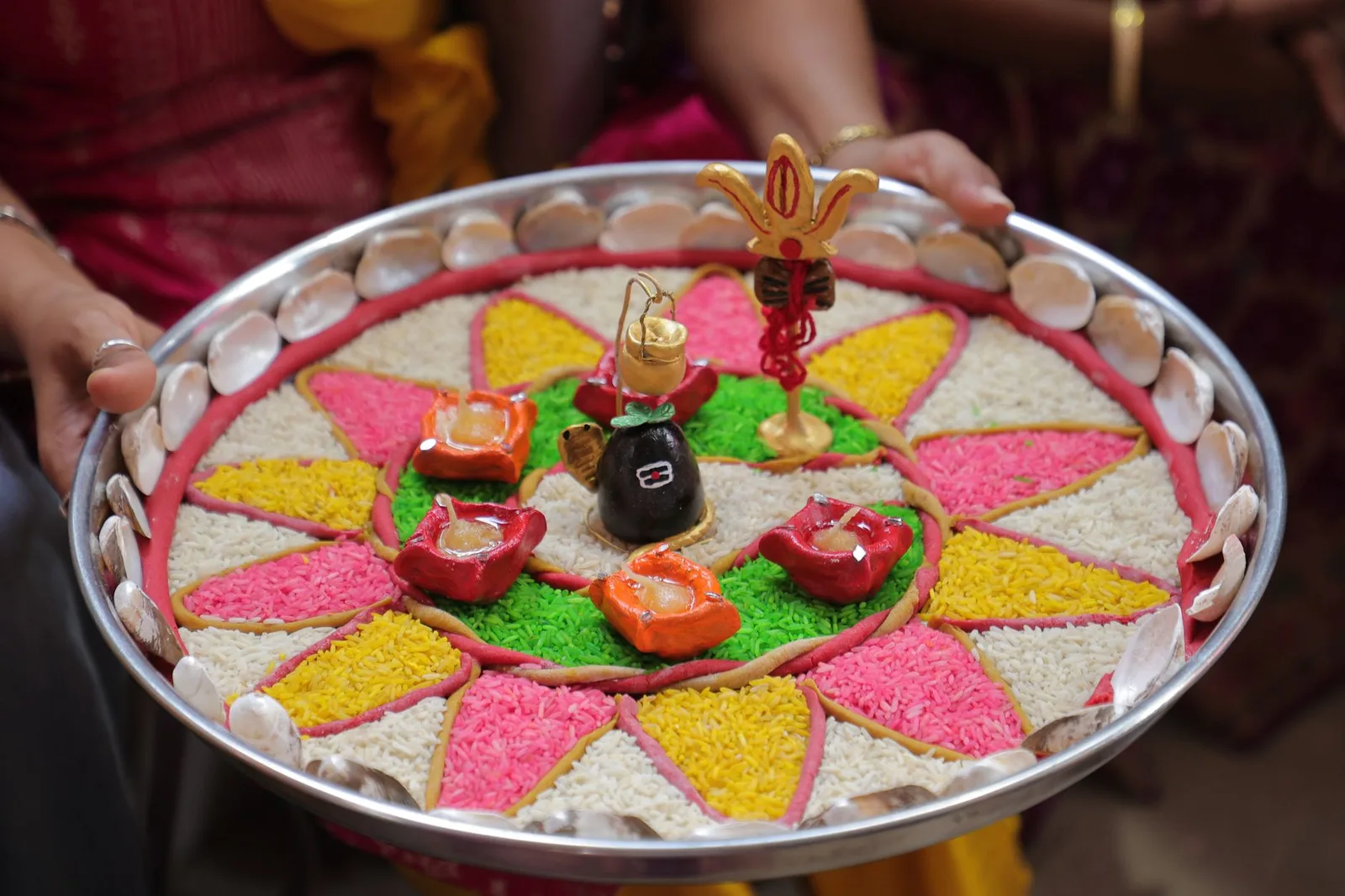 Vibrantly colored Indian Puja Thali decorated with rice and shells for a religious ceremony.