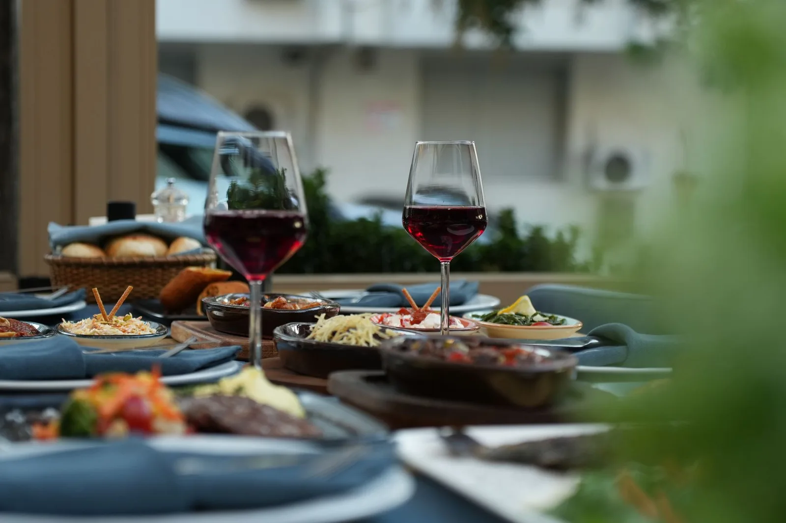 Luxurious outdoor table setting featuring red wine and a variety of gourmet dishes for a sophisticated dining experience