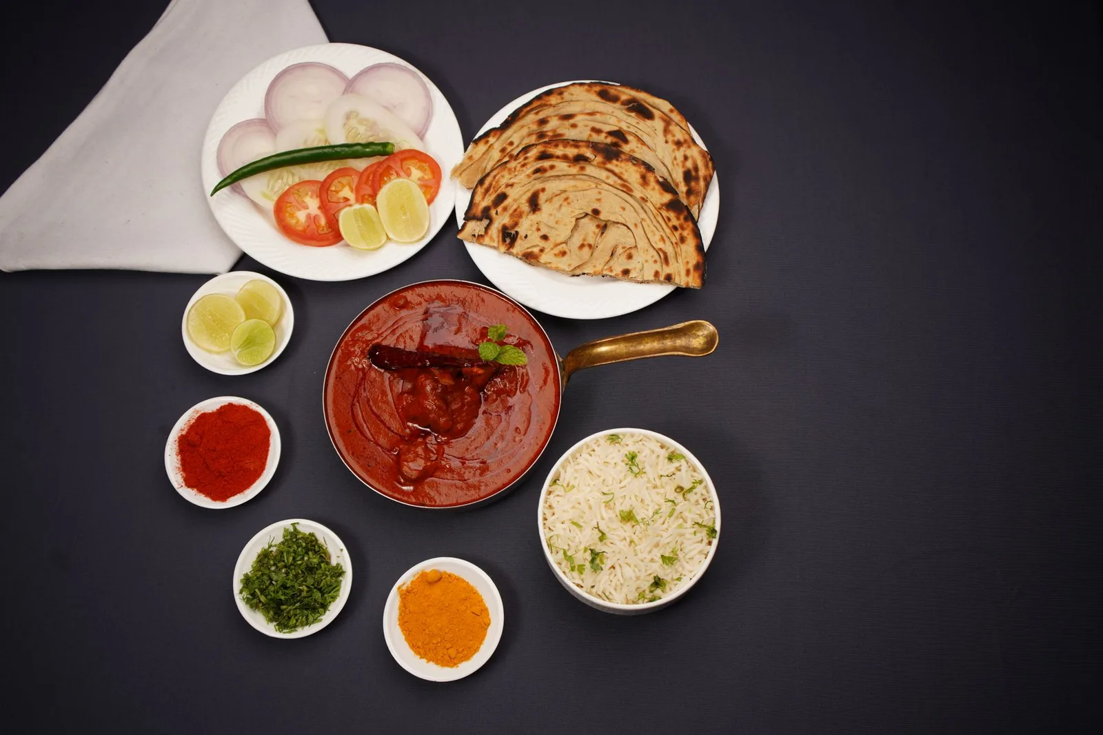 A vibrant Indian meal featuring spicy curry, flatbread, and fresh vegetables.