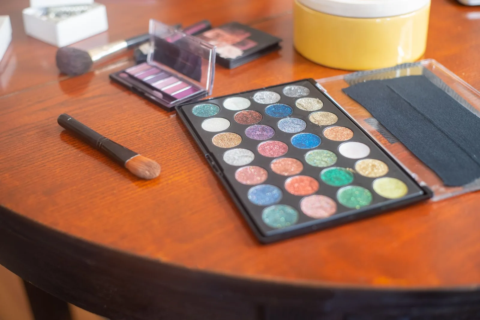 Vivid eyeshadow palette with vibrant colors on a wooden table, ideal for makeup professionals.
