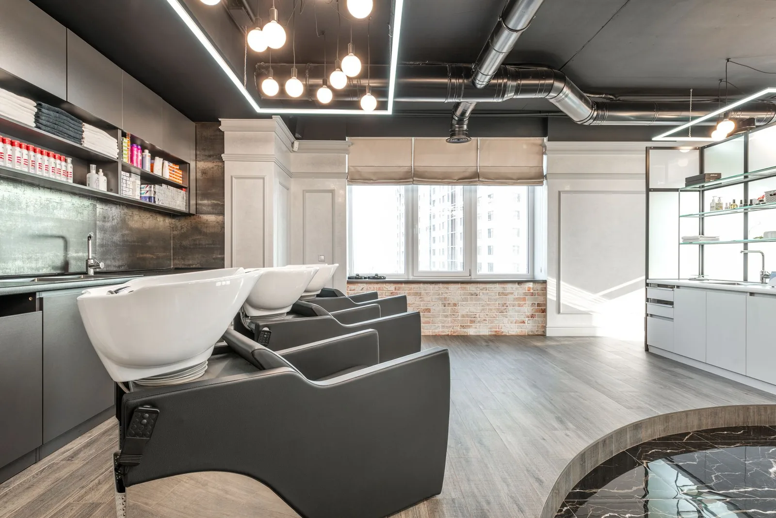 Black backwash chairs with sinks placed in modern spacious beauty salon with window and arrangement of cosmetology suppl