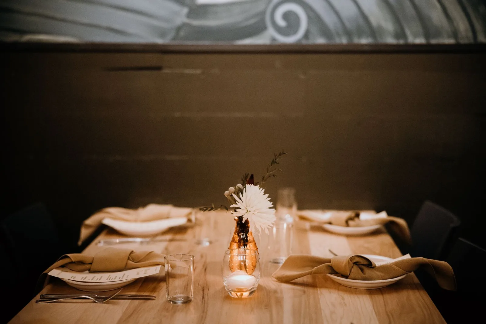 A beautifully set restaurant table with a candlelit centerpiece, ready for guests.