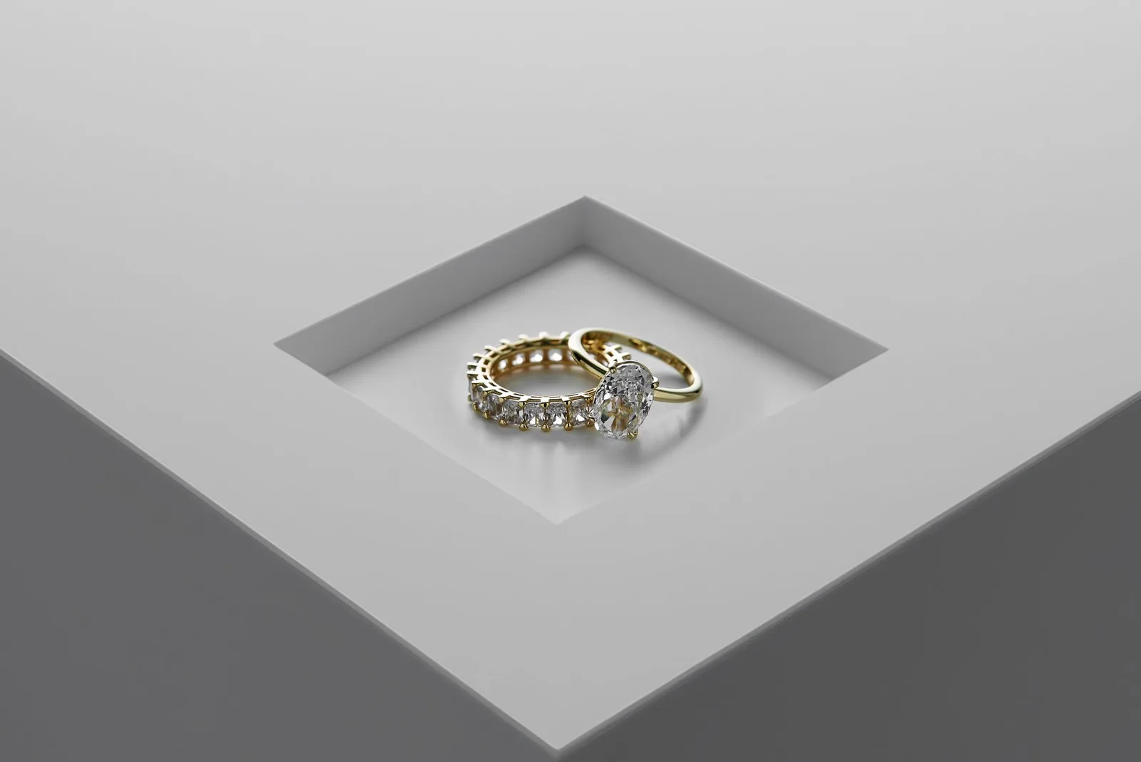 A close-up of exquisite gold and diamond rings set on a minimalist surface.